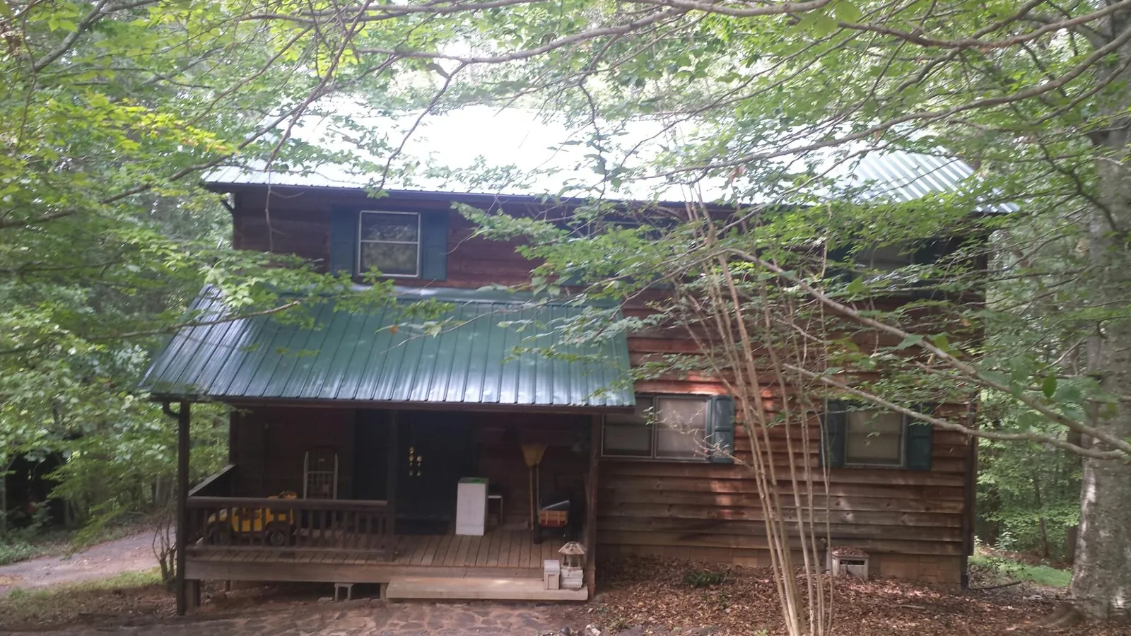 Green metal roof and covered porch on a log cabin in Palermo