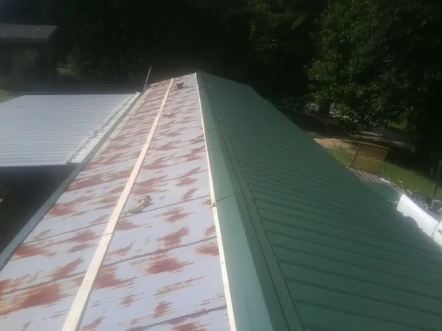 Old rusted panels beside newly installed green metal roofing — Wind Damage Roof Repair by Roofing Brothers in Palermo