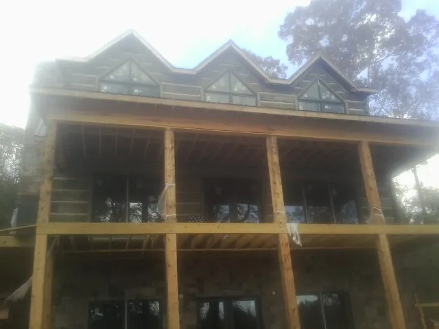 Dormers and porch framing on a large log home under construction — Roof Coating work by our crew in Palermo