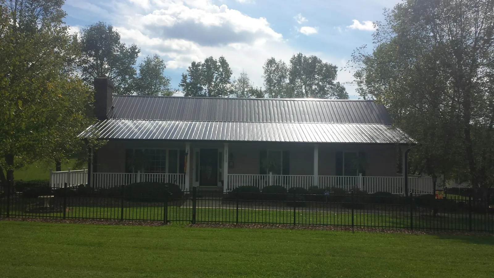 Gray metal roof on a brick ranch with a full width front porch — Gutter Guard Installation work by our crew in Palermo